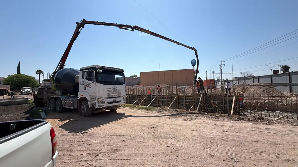 Camión revolvedor y bomba pluma extendida hacia una zona de trabajo con cimbra y acero